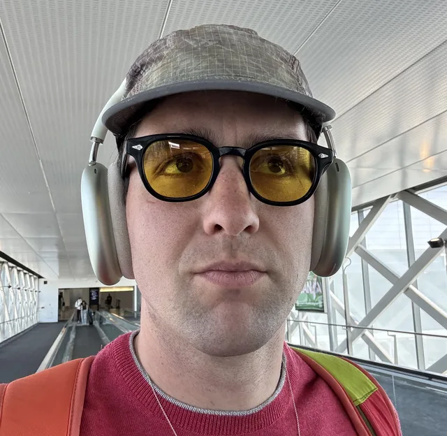 Graeme in a grey cap, headphones and yellow-tinted sunglasses