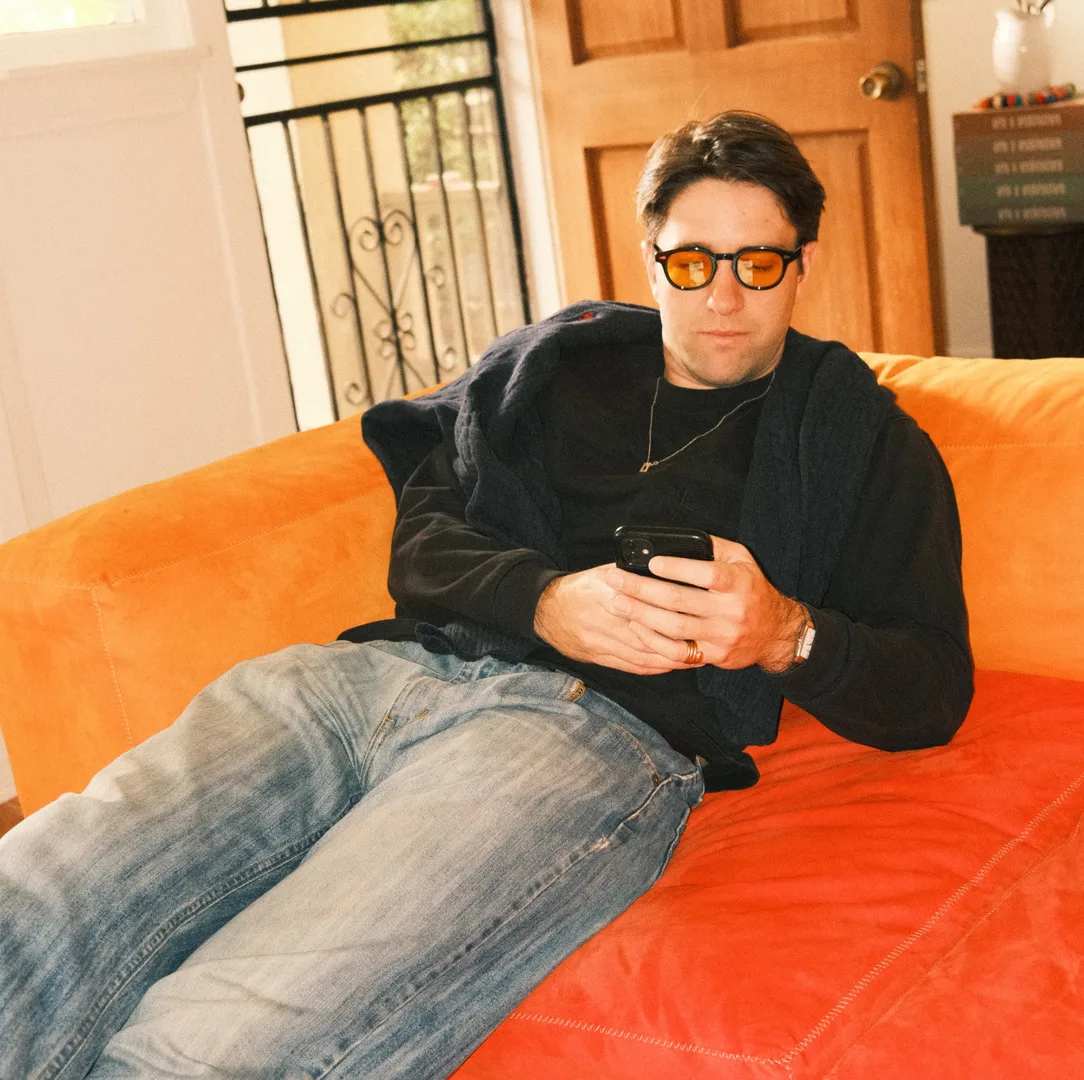 Graeme on an orange sofa, looking at his phone