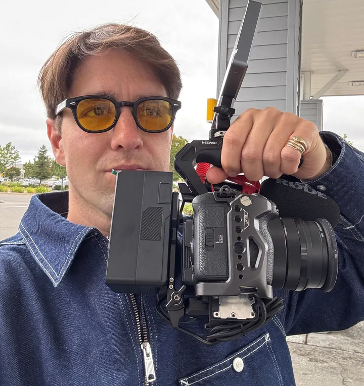 Graeme in yellow-tinted sunglasses, holding a cinema camera rig